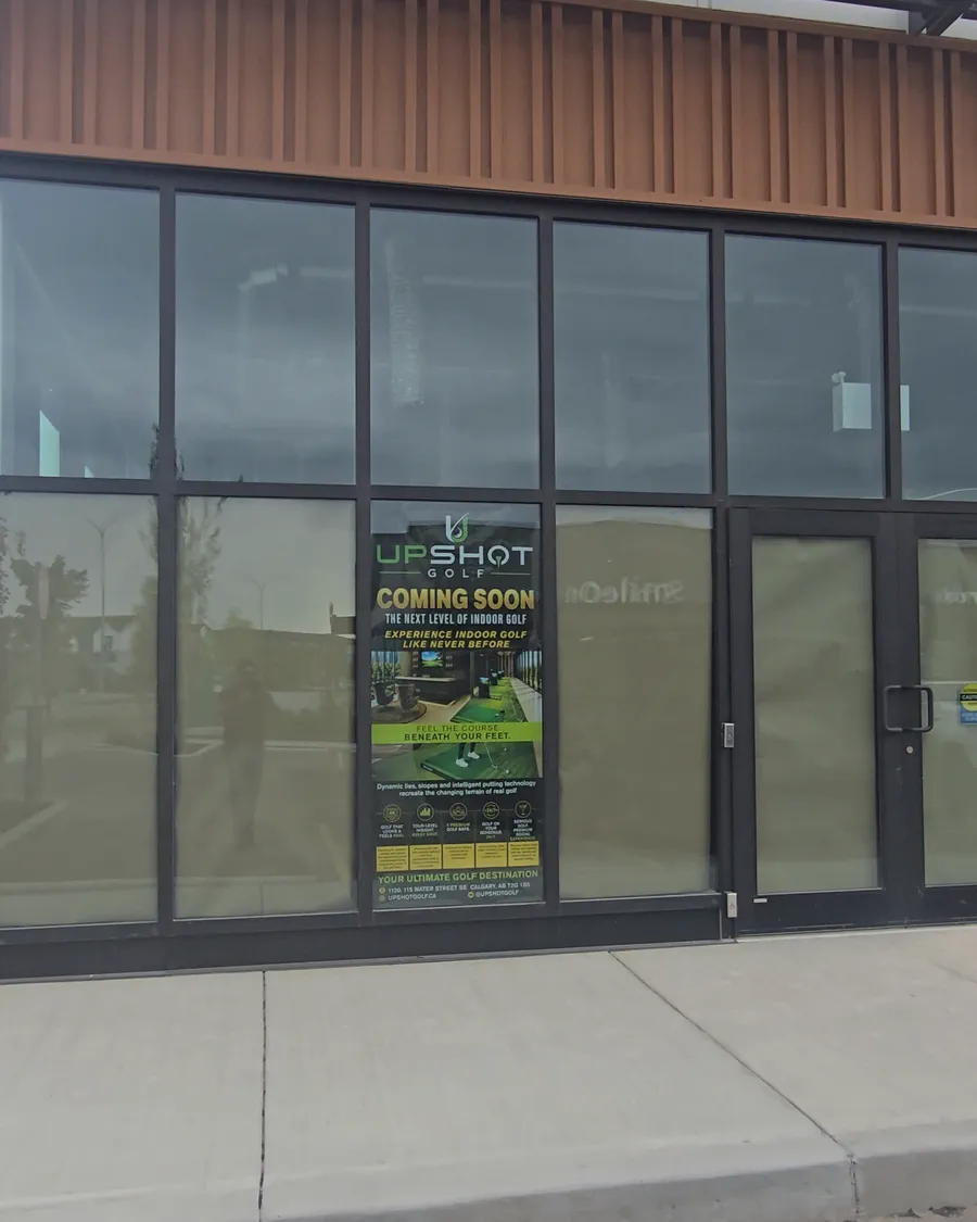 The UpShot Golf storefront on Water Street SE, with the green UpShot poster in the window beside the glass doors.